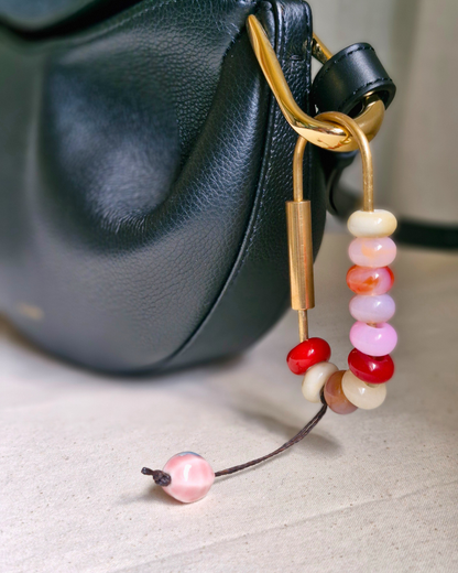 Bag charm de piedras naturales decorando cartera de cuero.