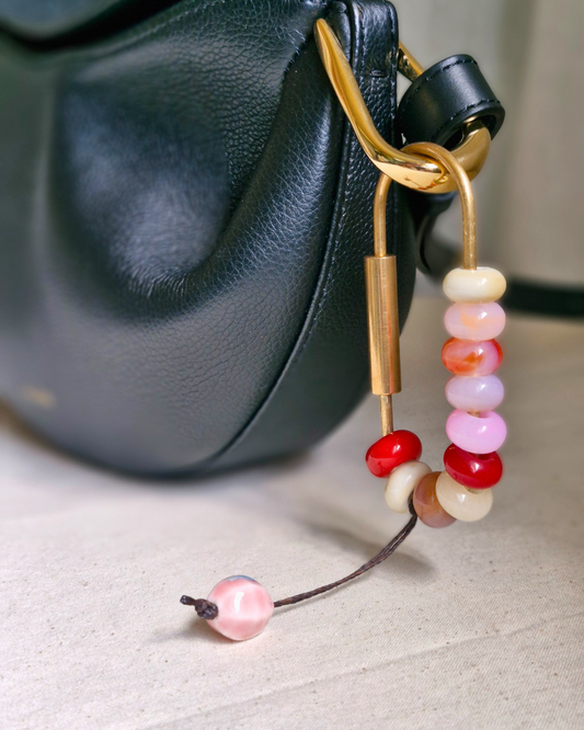 Bag charm de piedras naturales decorando cartera de cuero.