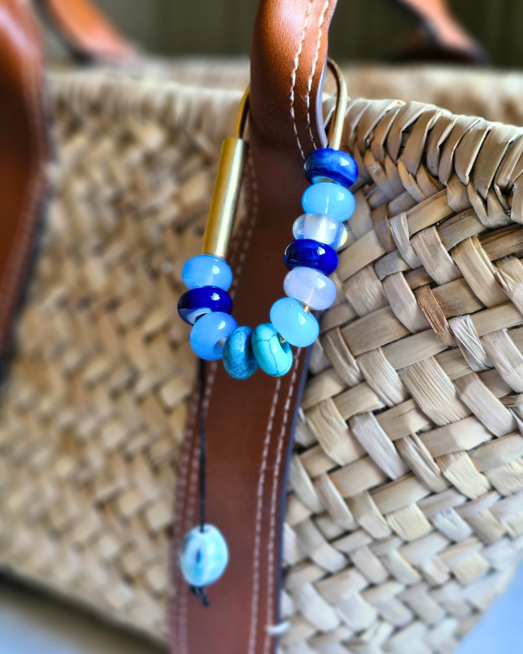 Bag charm artesanal con piedras naturales ópalo, jade y cuarzo colgando de bolso.