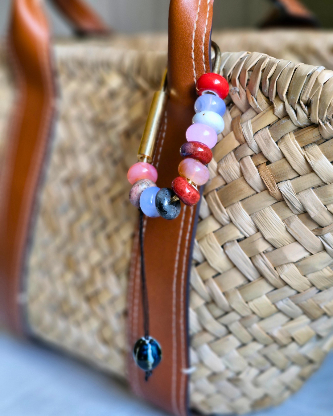 Bag charm artesanal con piedras naturales ópalo, jade y cuarzo colgando de bolso.