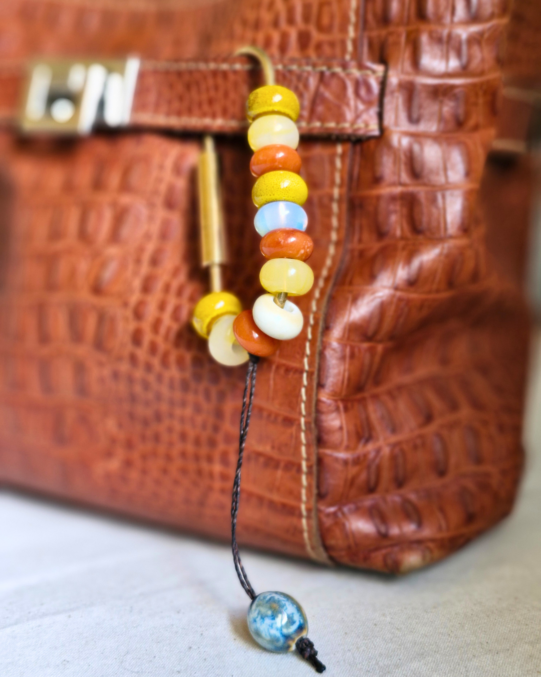 Bag charm de piedras naturales decorando cartera de cuero.