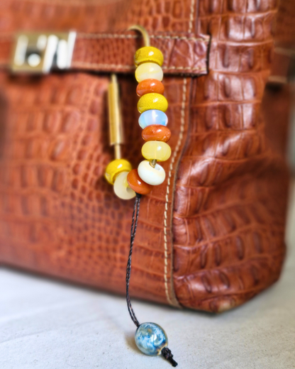 Bag charm de piedras naturales decorando cartera de cuero.