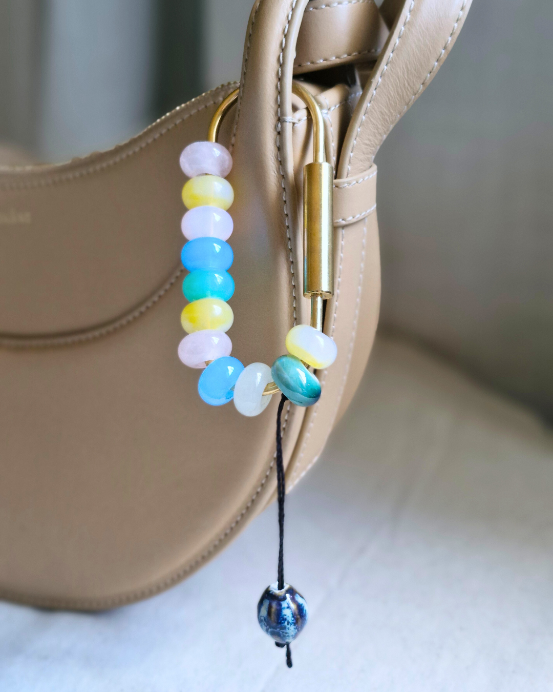 Bag charm artesanal con piedras naturales ópalo, jade y cuarzo colgando de bolso.