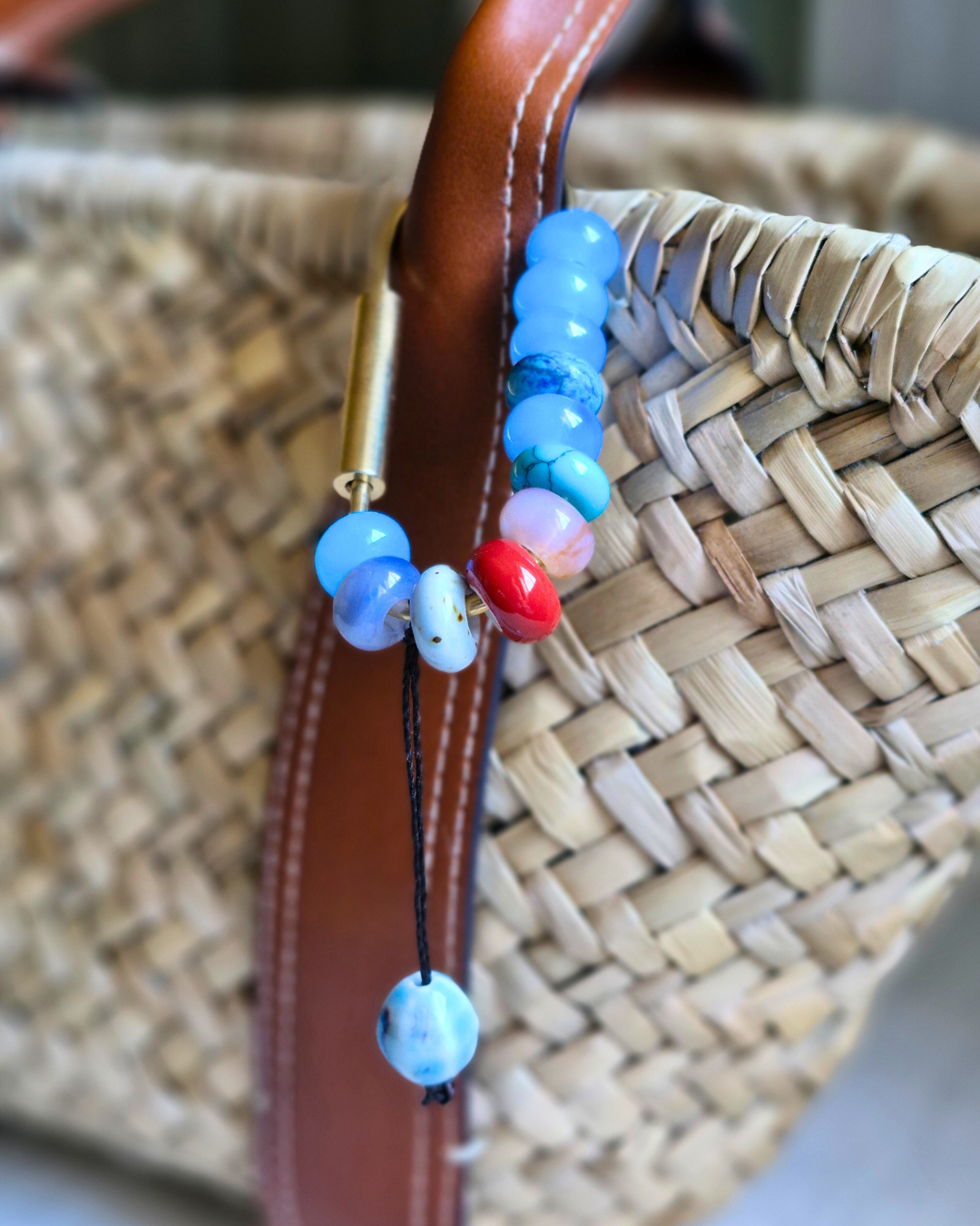 Bag charm artesanal con piedras naturales ópalo, jade y cuarzo colgando de bolso.