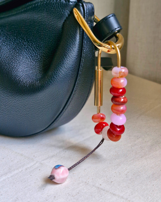 Bag charm de piedras naturales decorando cartera de cuero.